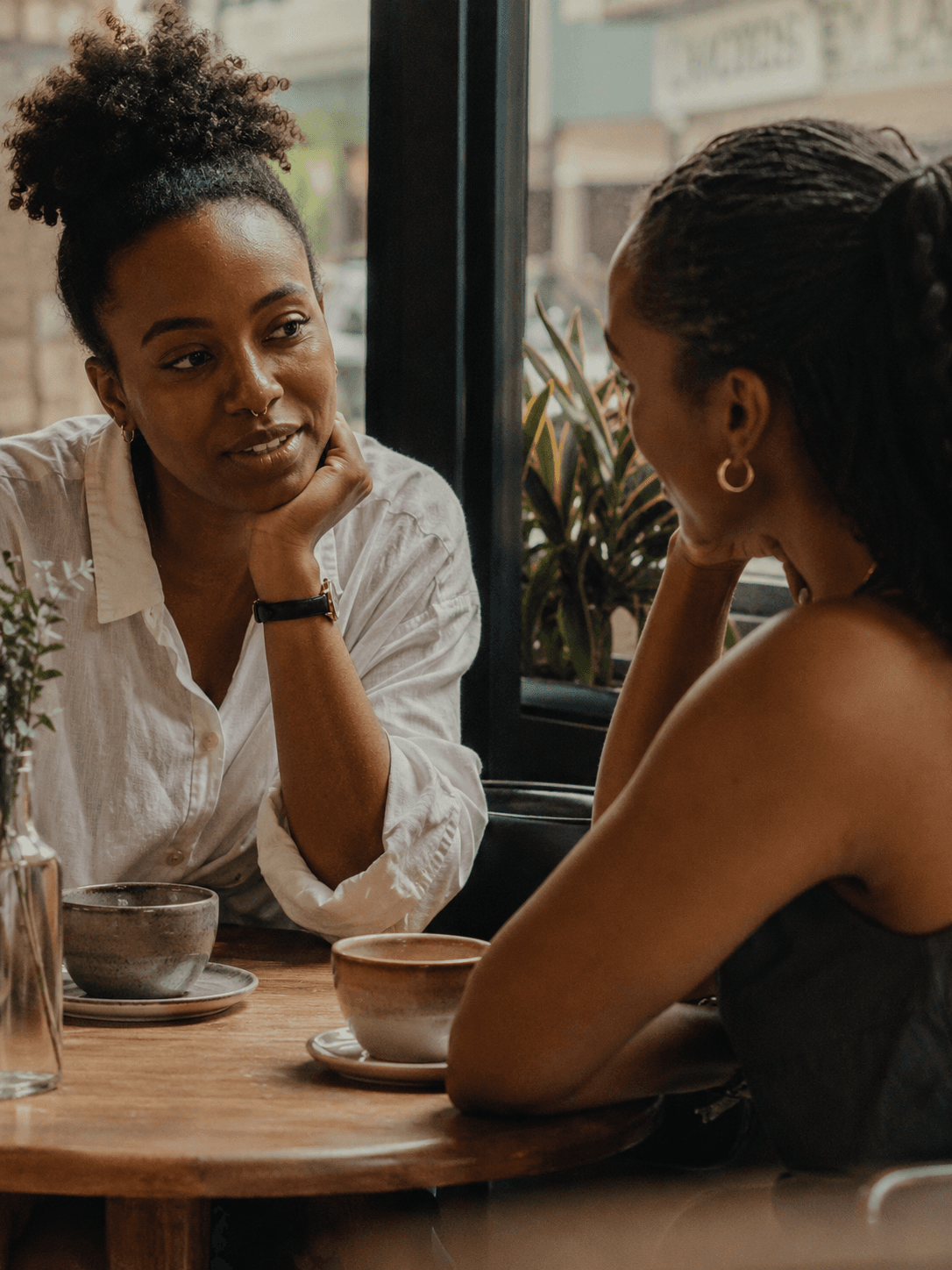 Two women talking over coffee at a small café table